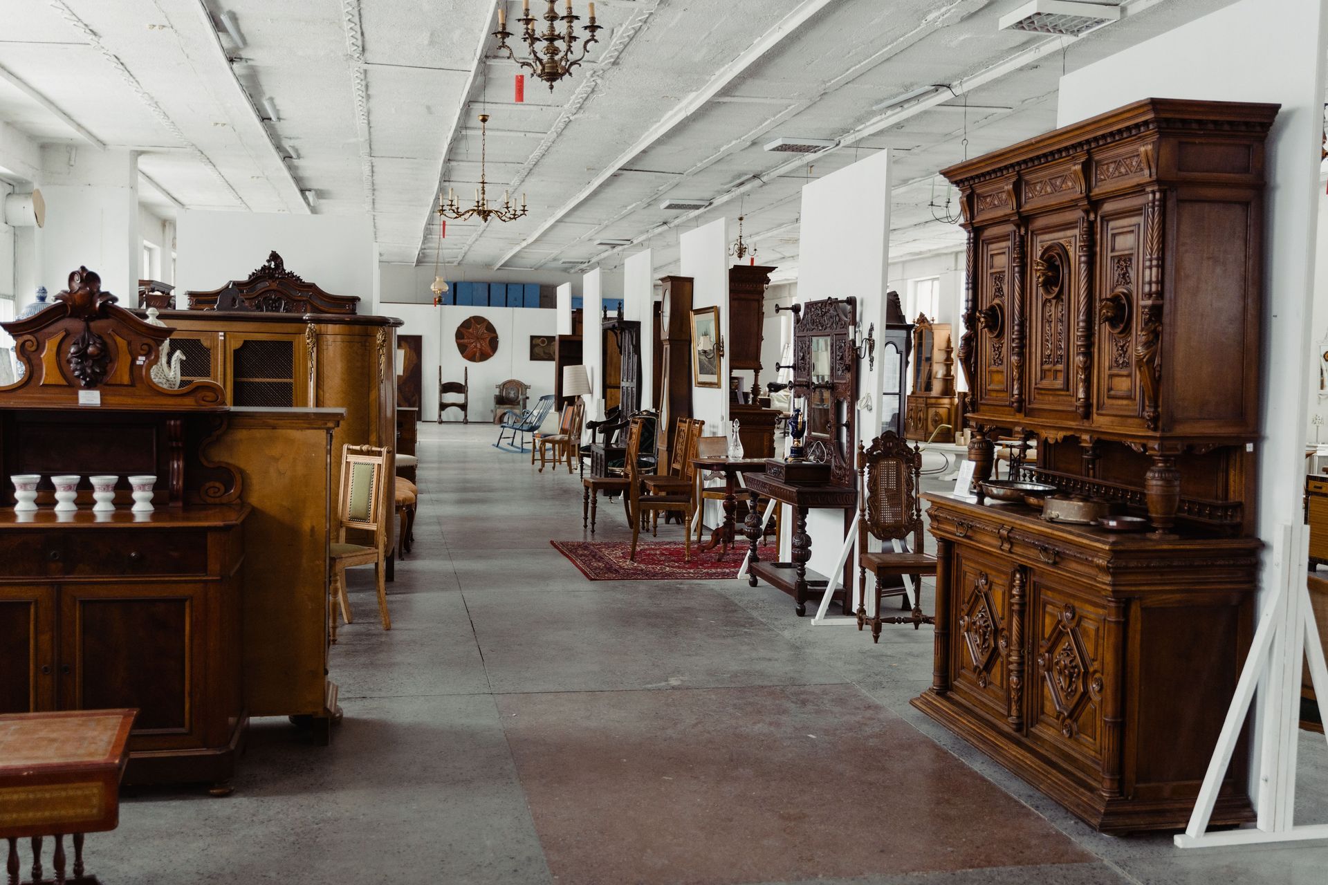 Antique furniture showroom with carved wooden cabinets and chairs arranged in a bright hall