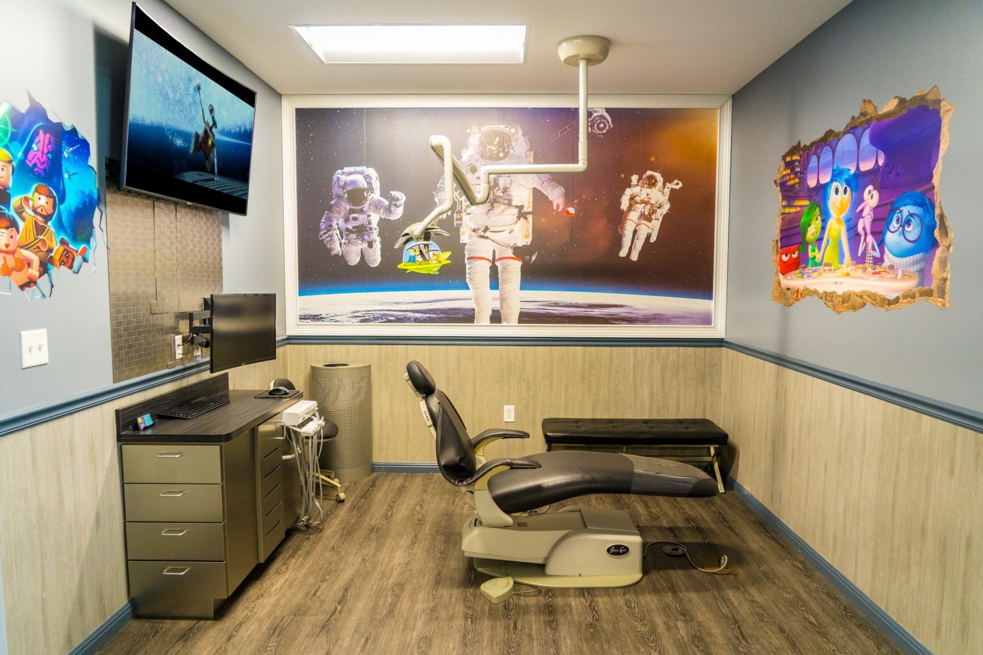 Modern rehab therapy room with exercise equipment, wall murals, and a TV mounted on the left.