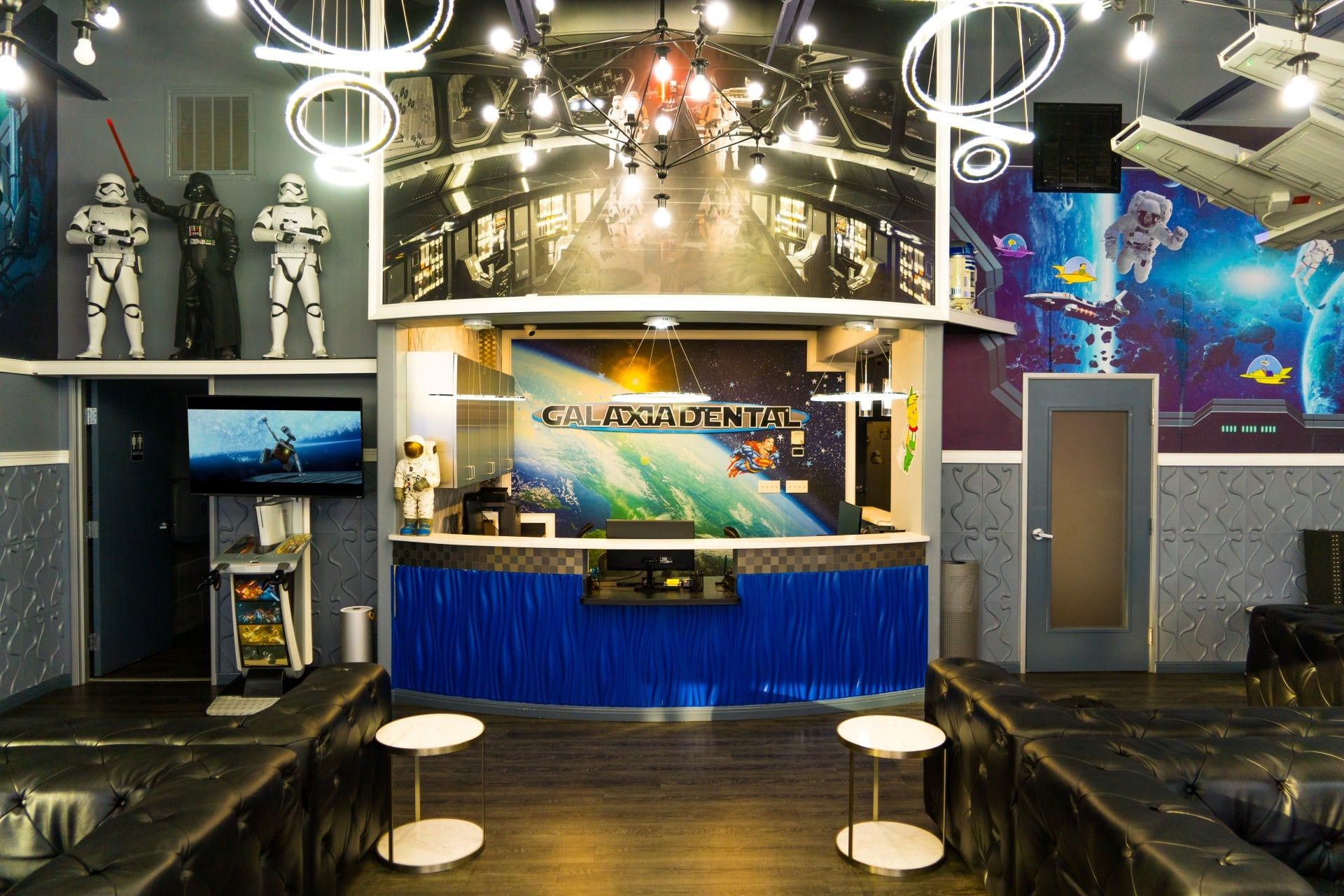 Modern sci-fi themed lounge with black leather seating, neon ring lights, and space-themed wall art.