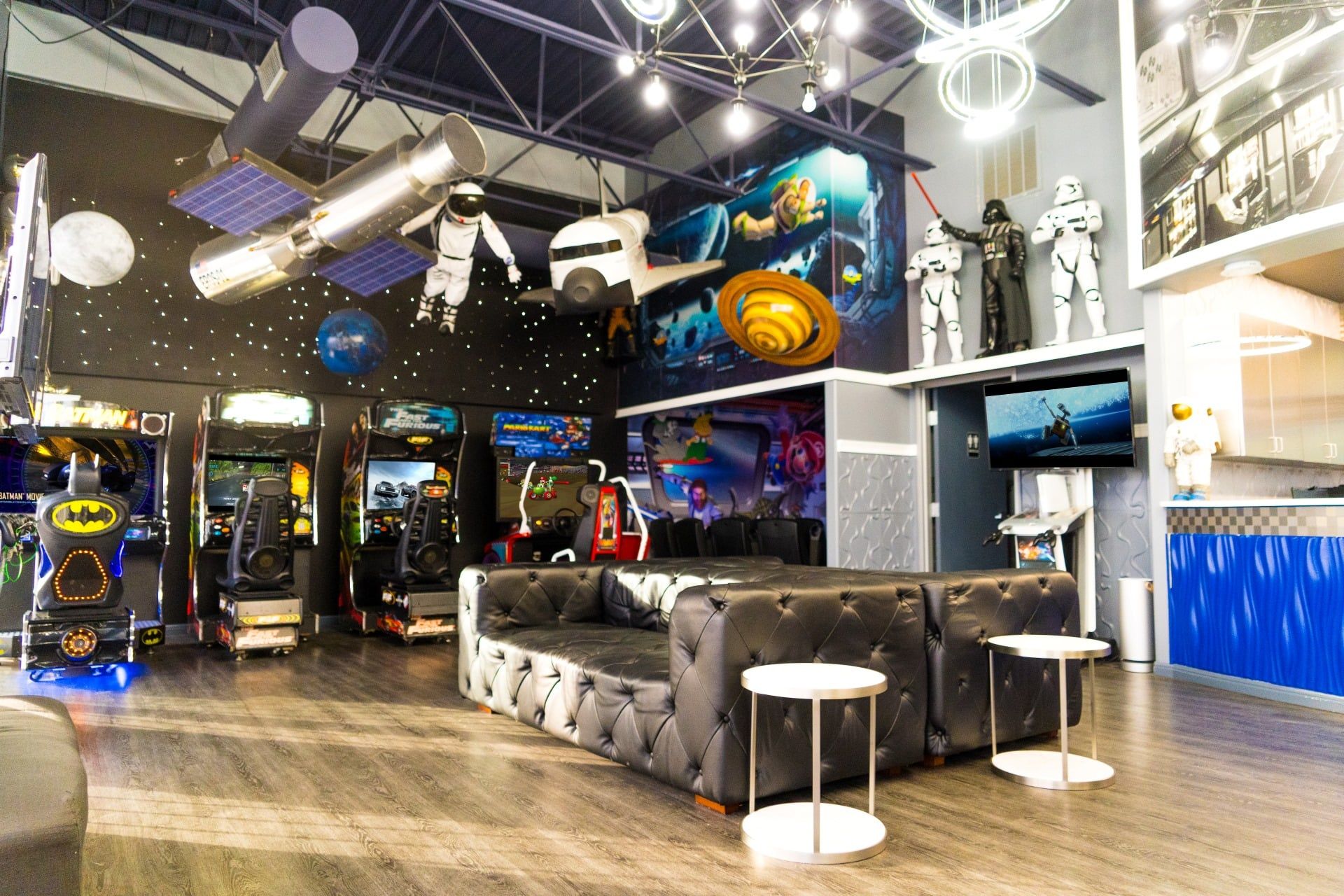 Modern arcade lounge with black tufted seating, neon lights, and game machines in a colorful interior