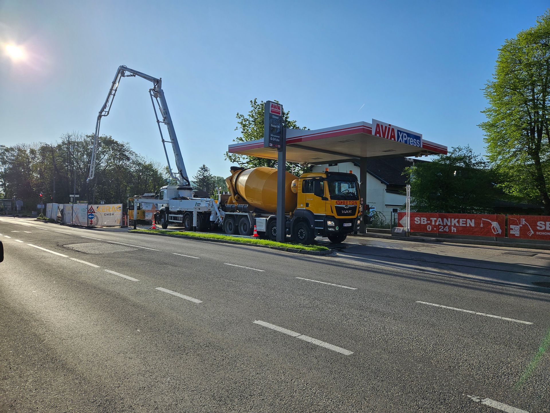Betonmischer gießt Beton auf einer Tankstellenbaustelle unter blauem Himmel.