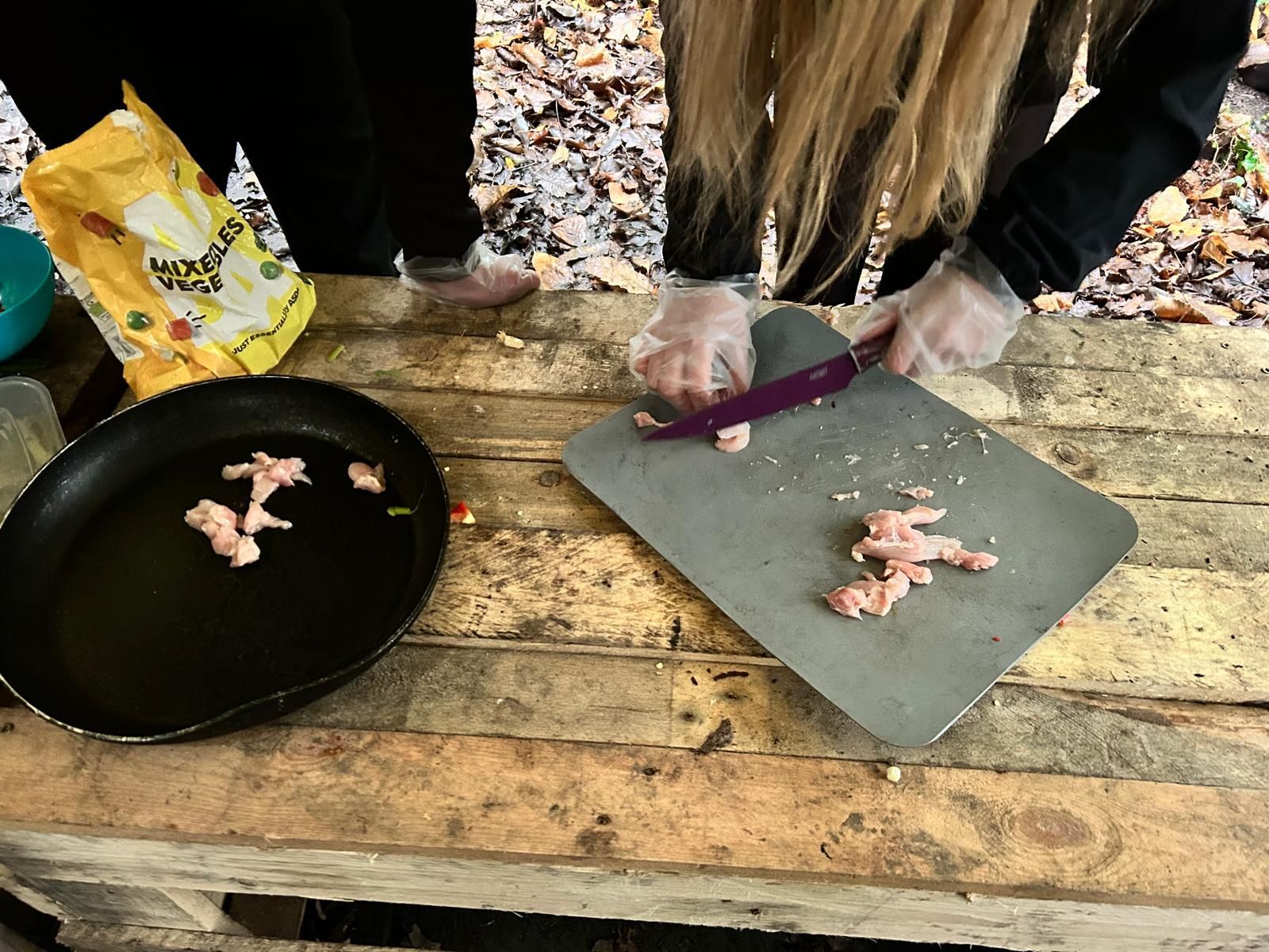 A woman is cutting meat on a cutting board.