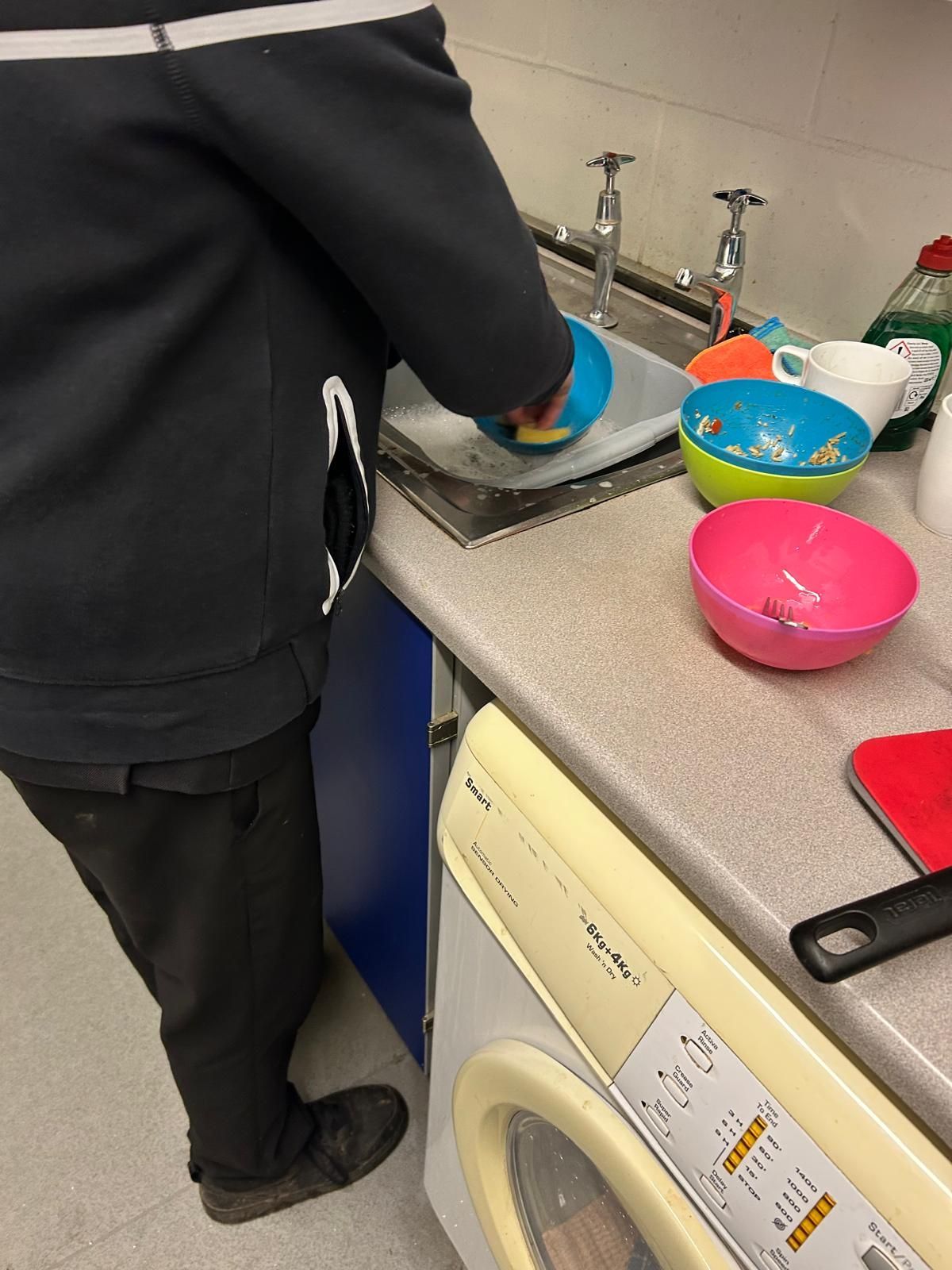A person is washing dishes in a kitchen sink.