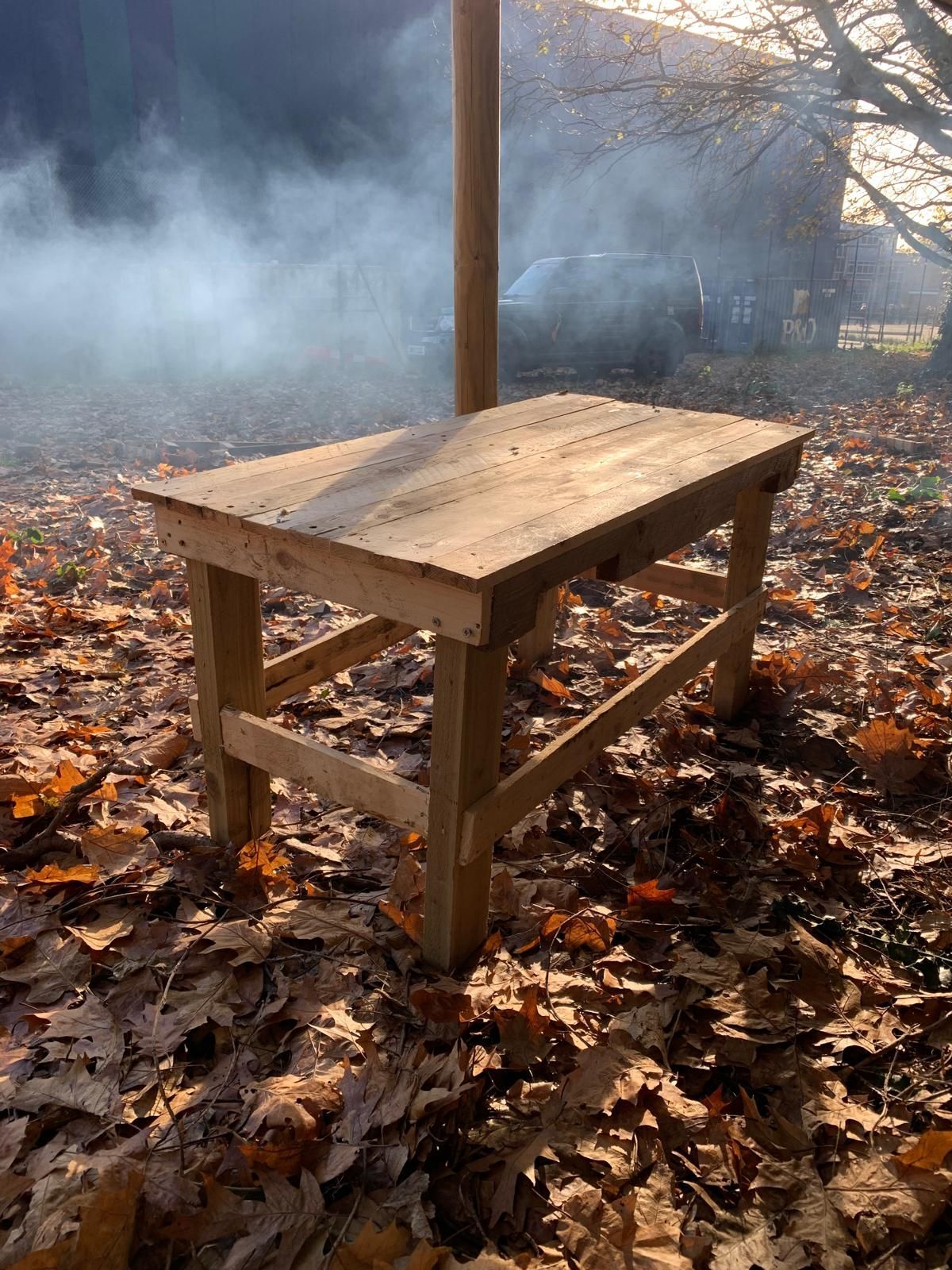 A wooden table is sitting on top of a pile of leaves.