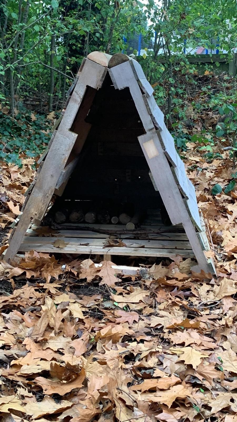 A small wooden structure is sitting in the middle of a pile of leaves.