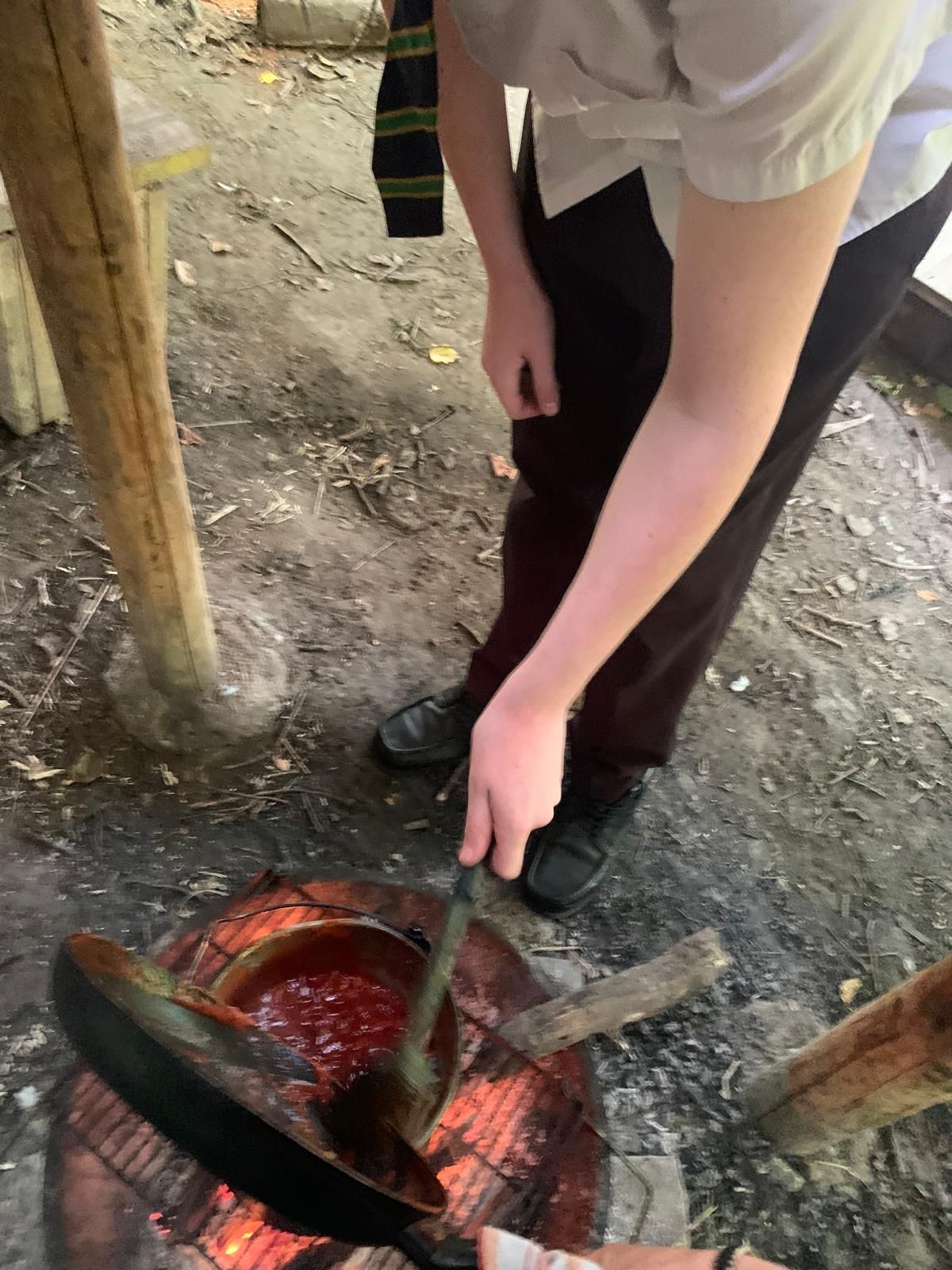 A person is cooking food in a pan over a fire.