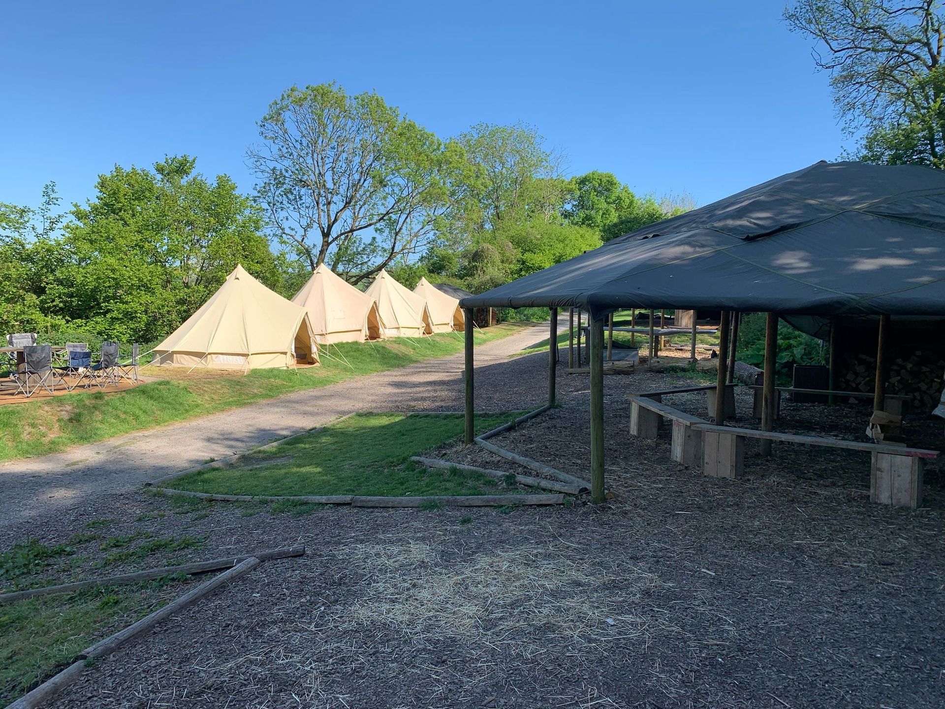 A group of tents are sitting on top of a grassy hill next to a shelter.