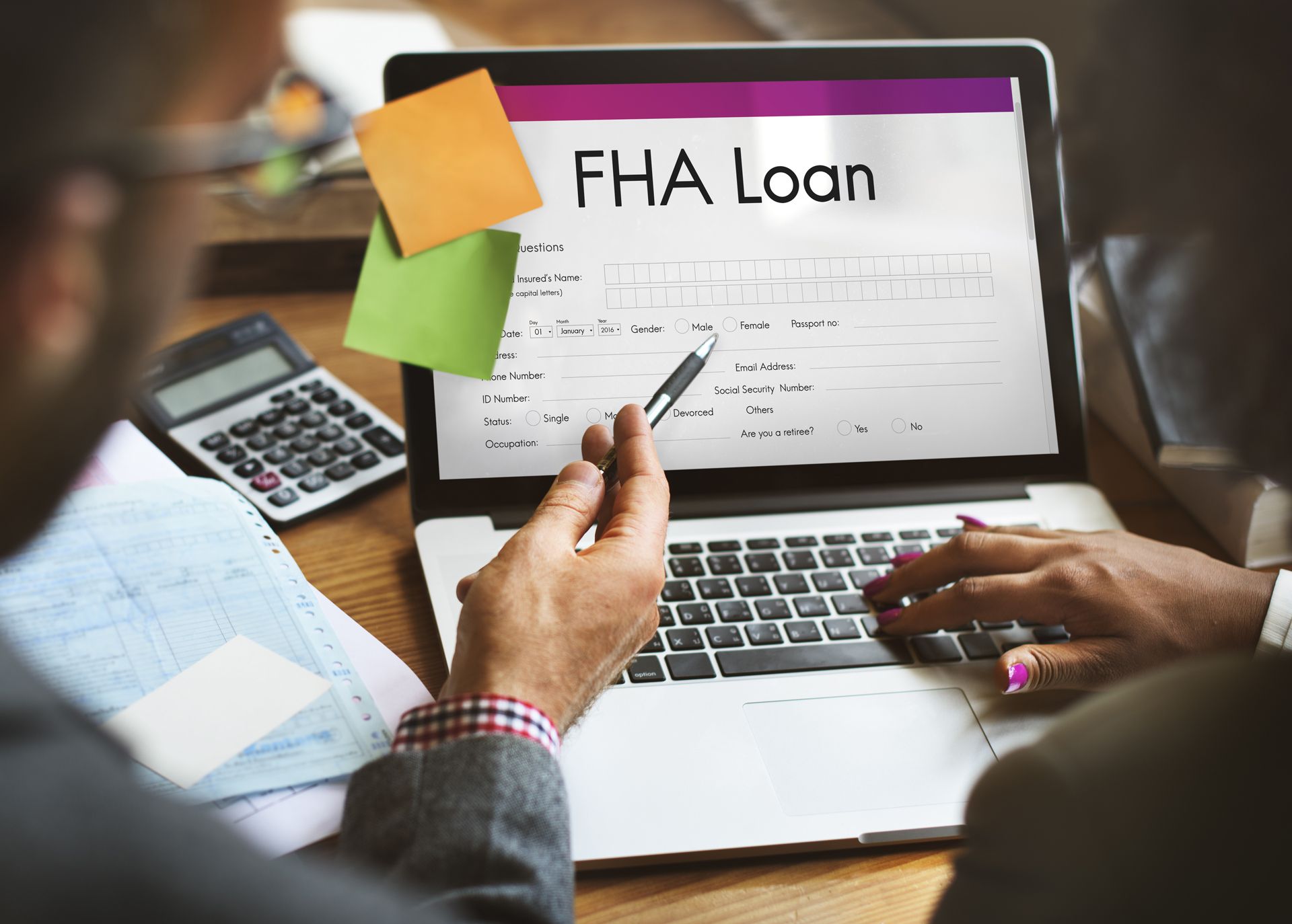 Two people review an FHA loan form on a laptop