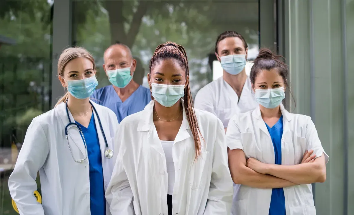 A group of doctors and nurses wearing face masks are posing for a picture.