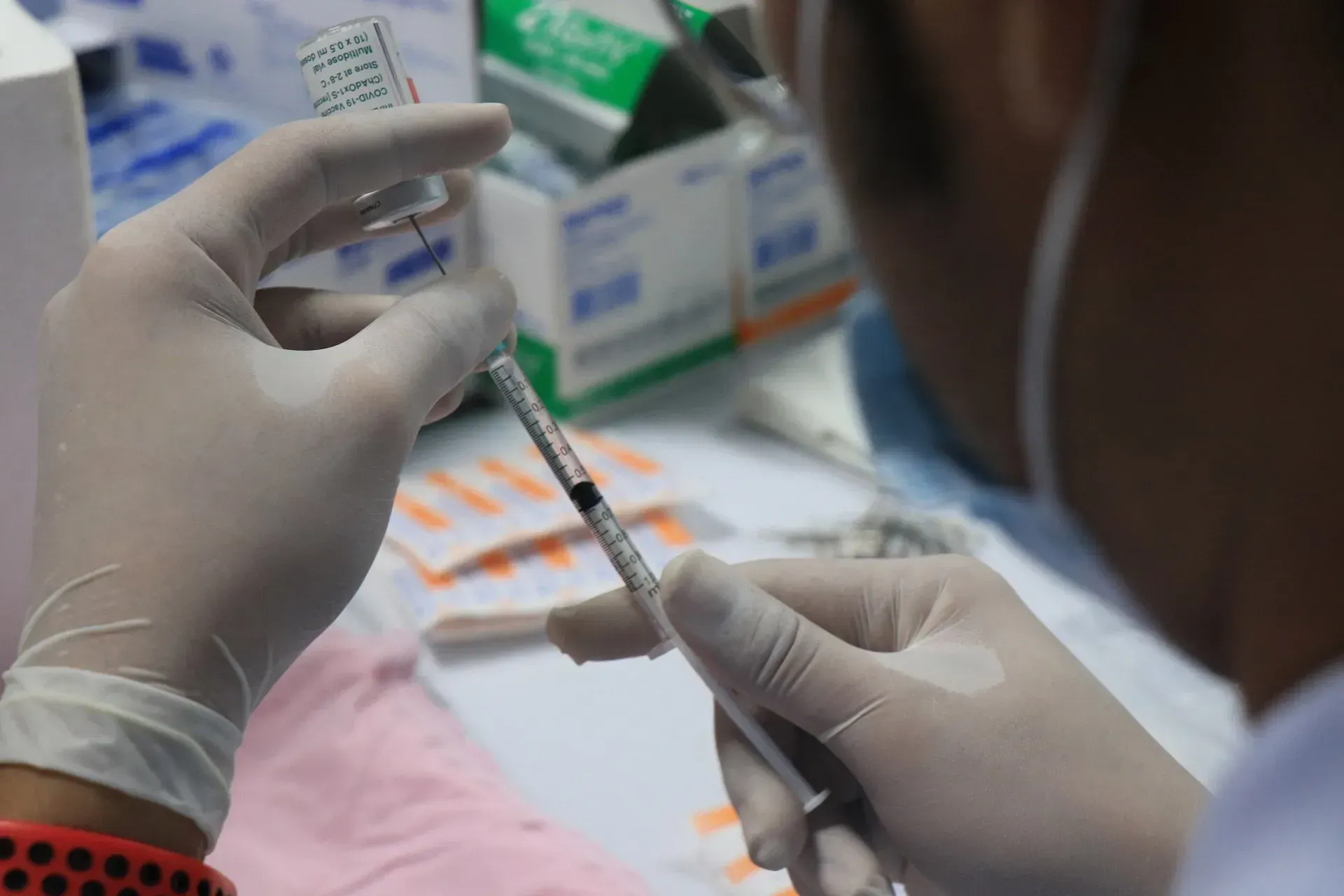 A person is holding a syringe and a bottle of vaccine.