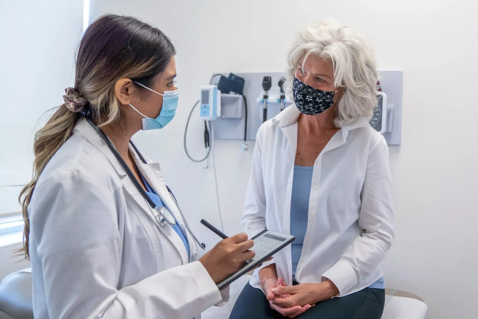 A doctor is talking to a patient who is wearing a mask. A doctor is talking to a patient who is wearing a mask.