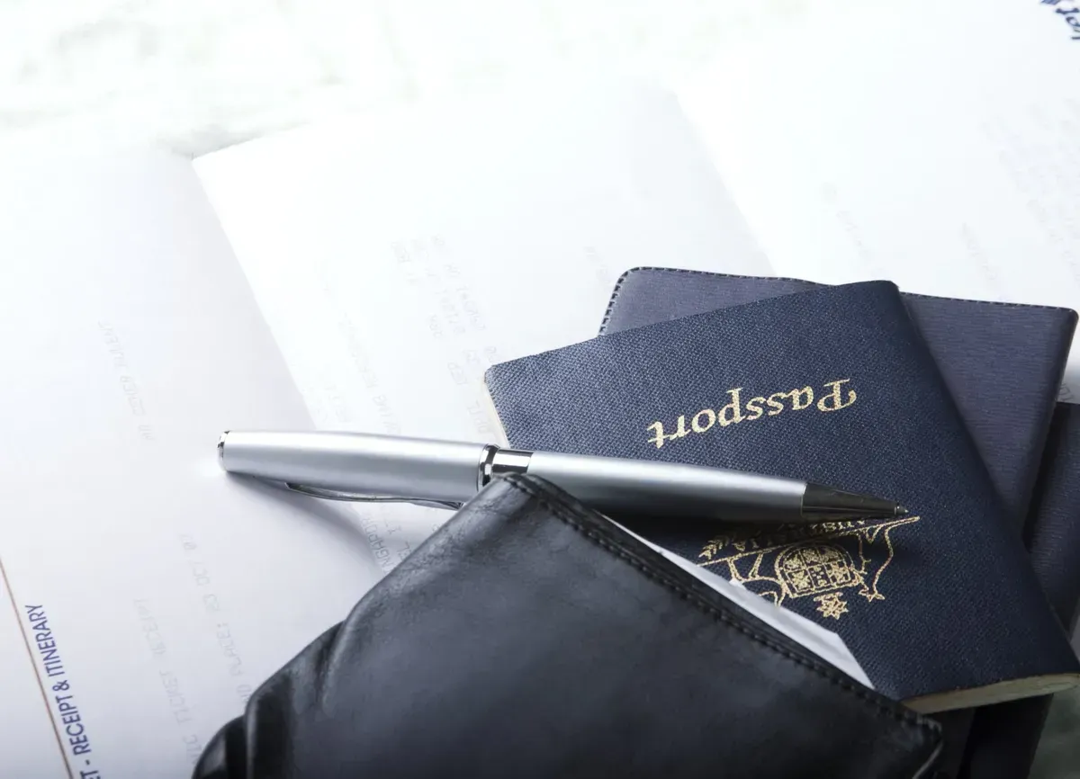 Two passports and a pen on top of a wallet Two passports and a pen on top of a wallet