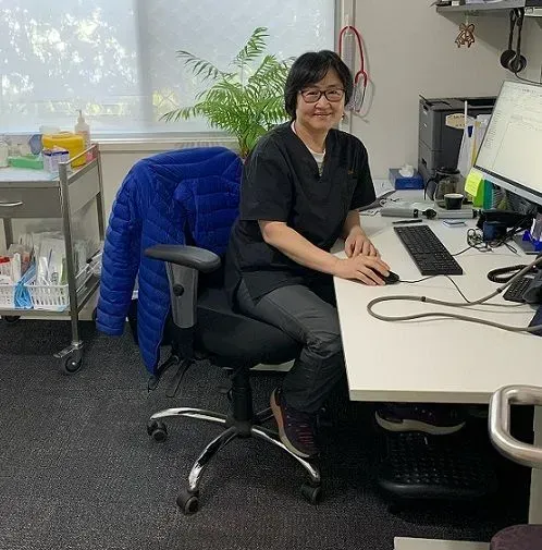 A woman is sitting at a desk in front of a computer.