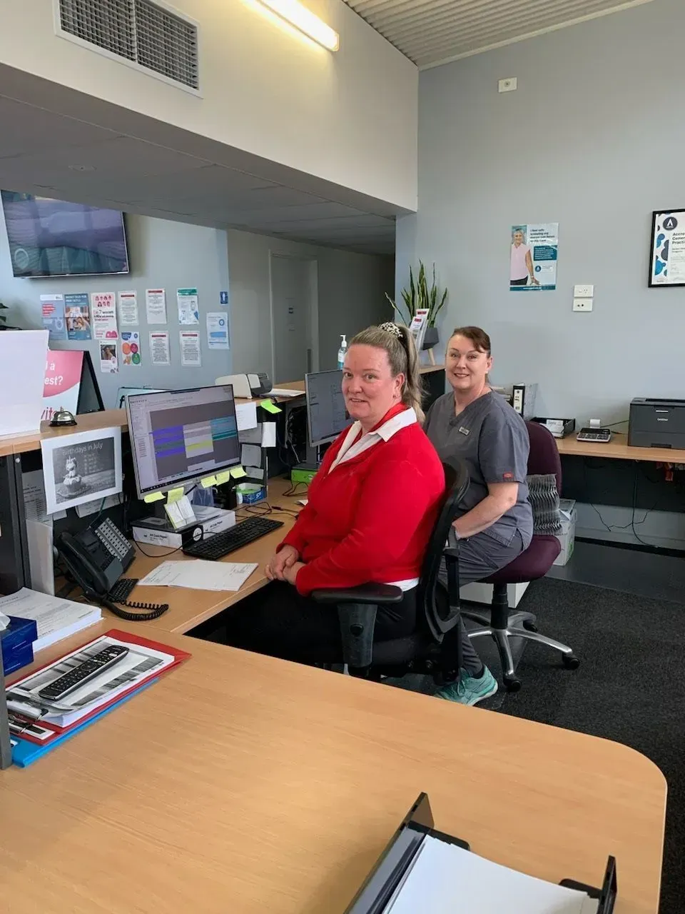 Two women are sitting at desks in an office.