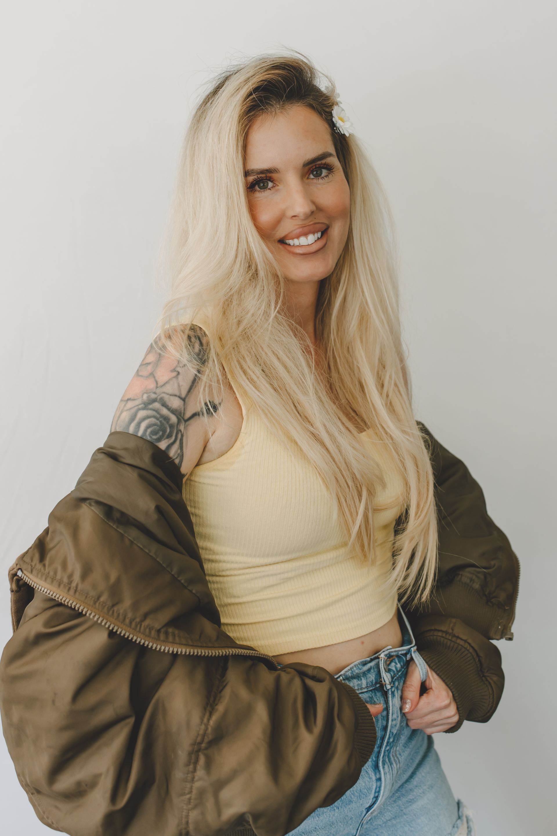 Smiling woman with shoulder-length blonde hair in a light gray T-shirt against a plain wall