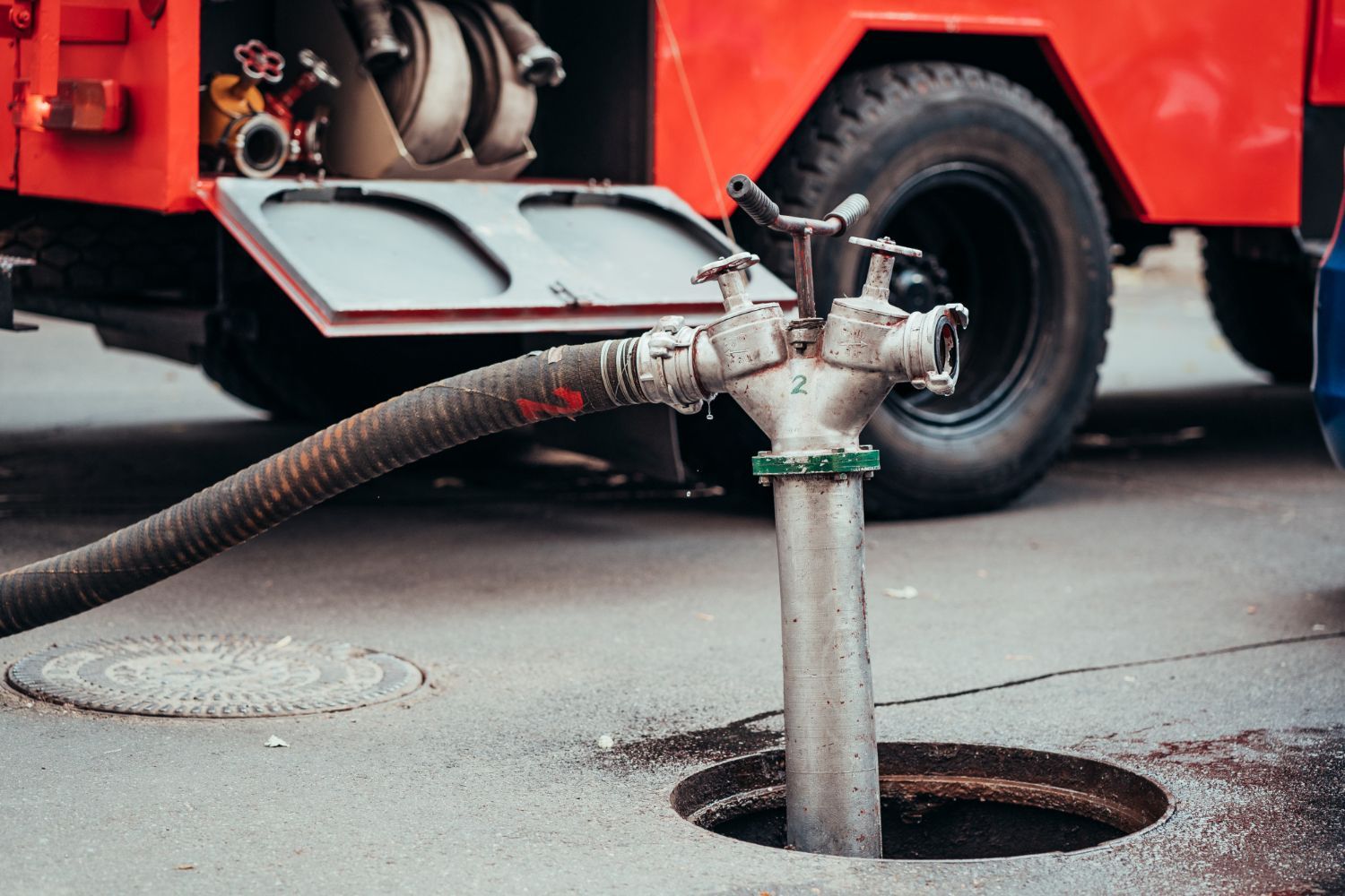 A fire truck is pumping water into a manhole.