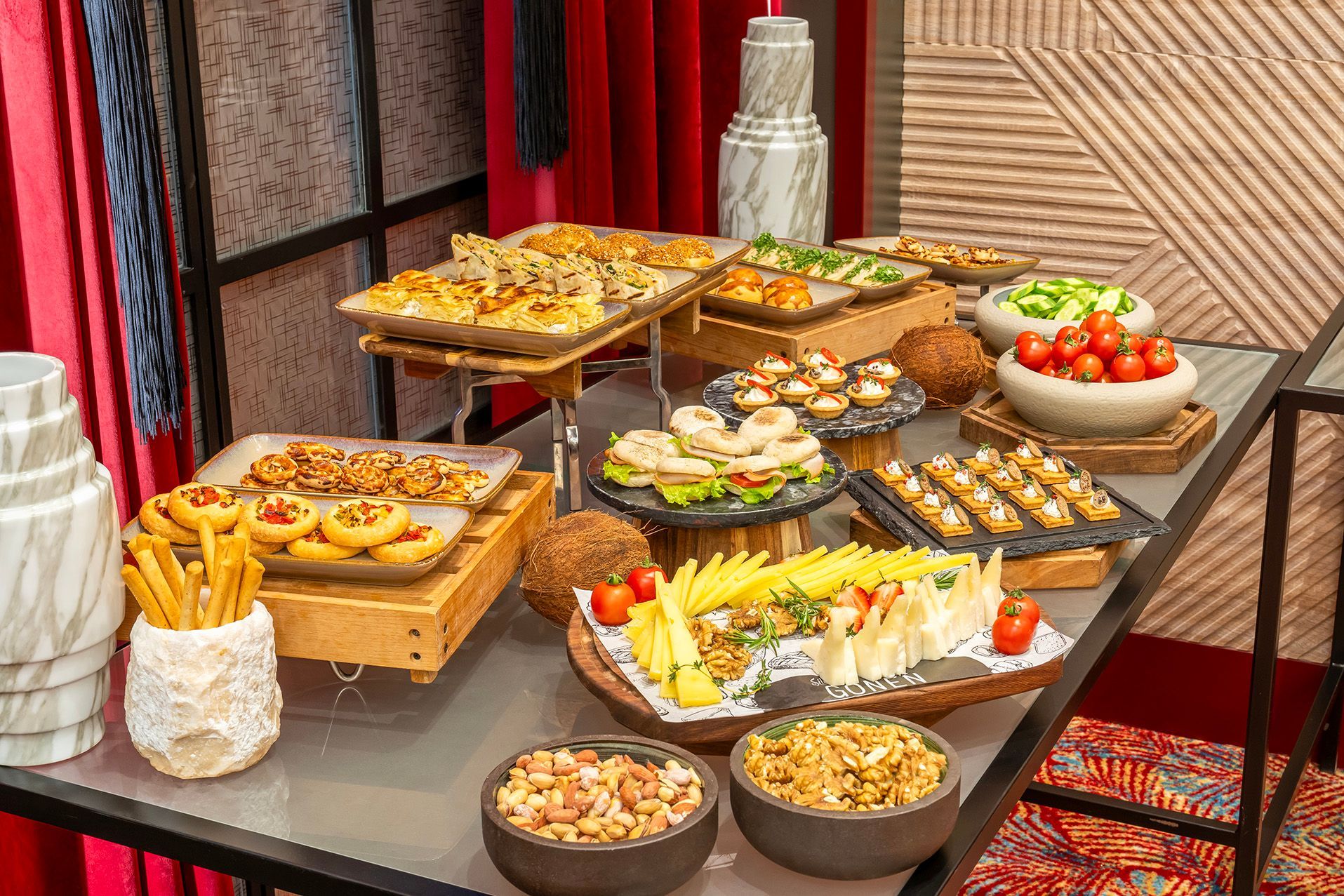 Buffet table with assorted appetizers, pastries, fruits, and desserts in a warm indoor setting