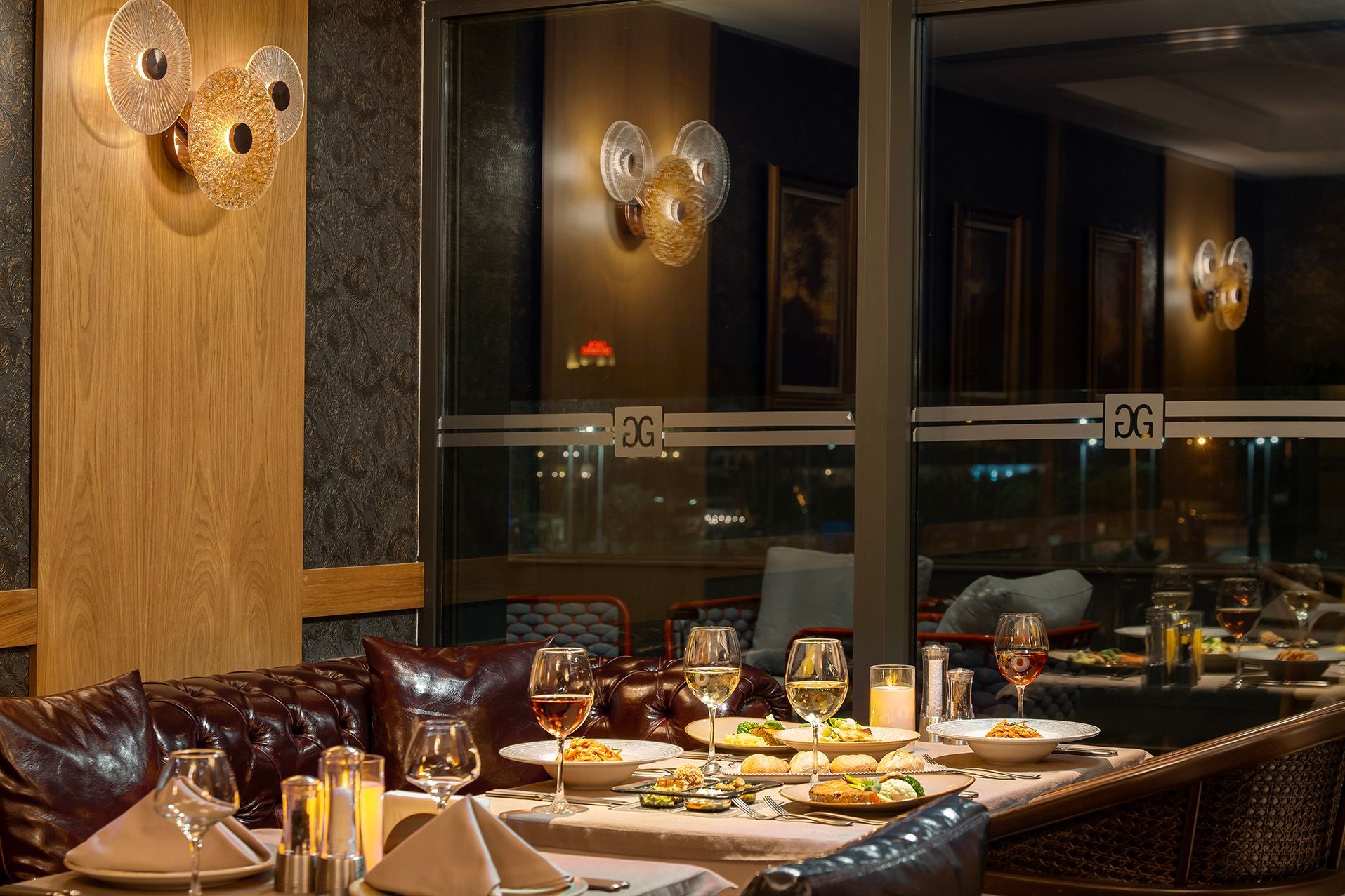Elegant restaurant booth by a window, set with plates and drinks at night
