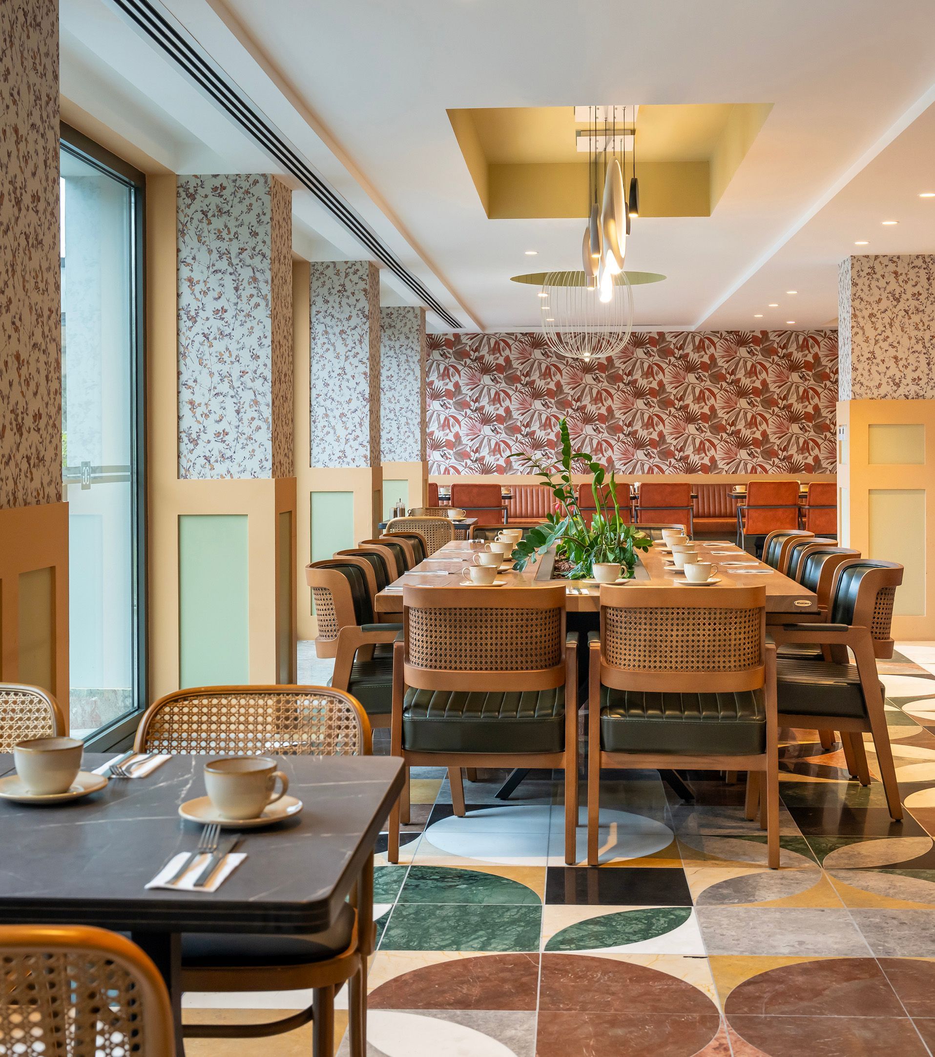 Modern restaurant dining room with wooden tables, woven chairs, and patterned tile flooring