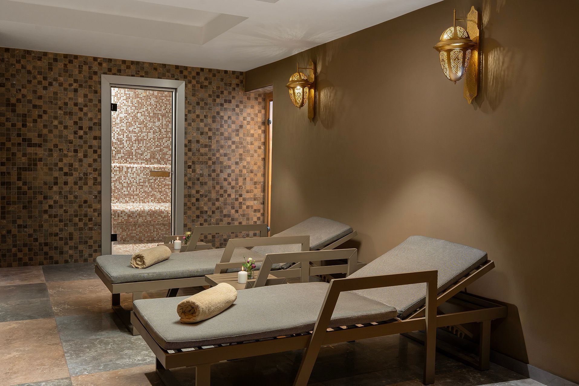 Spa room with two massage tables, warm wall lights, and a tiled doorway