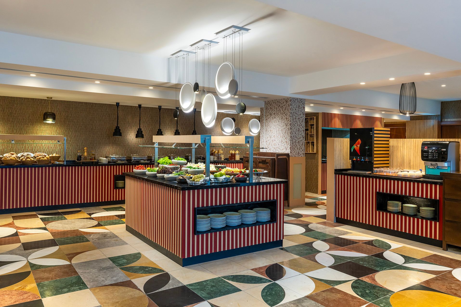 Modern buffet restaurant with colorful geometric floor, striped counters, and hanging lights