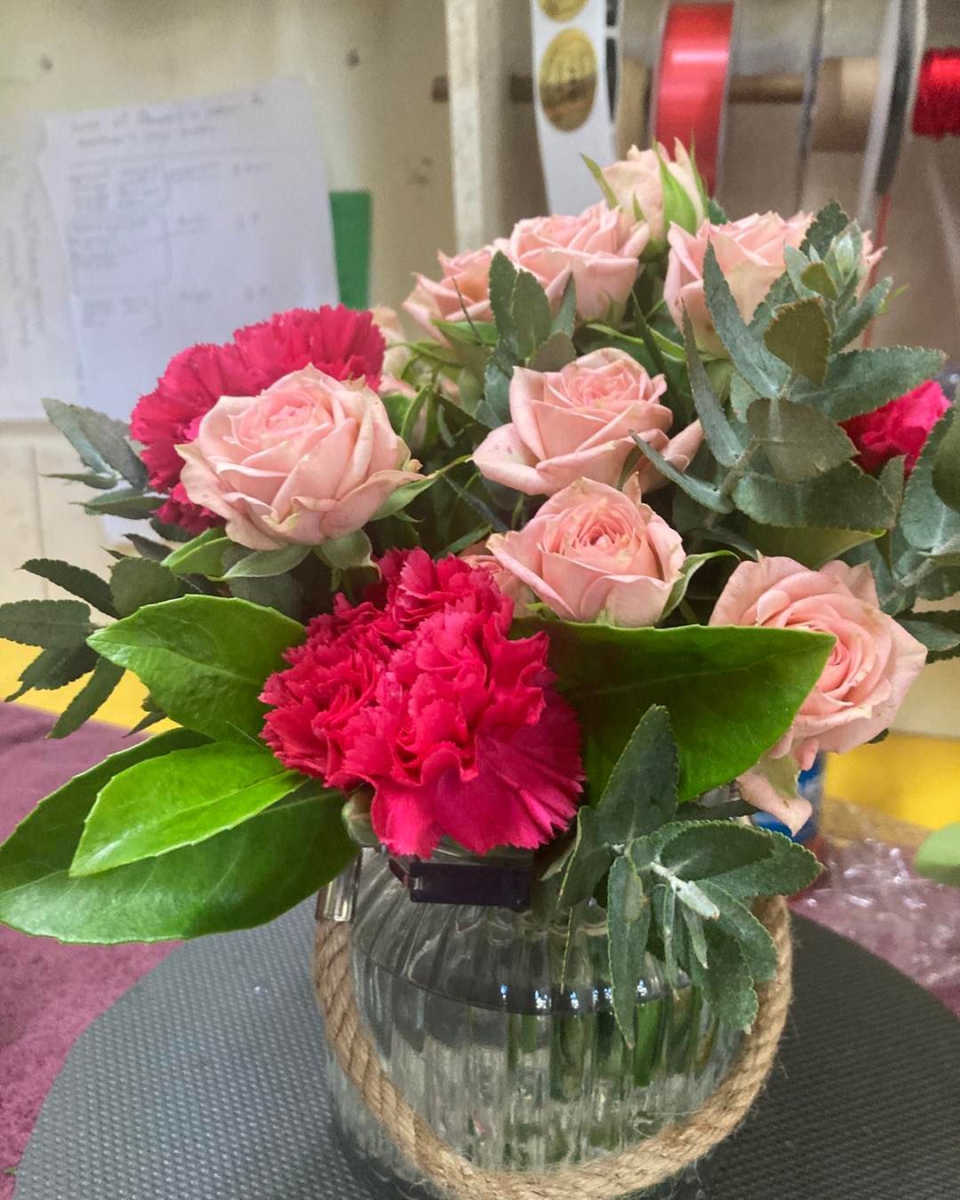 A Vase Filled With Pink Roses and Red Carnations is Sitting on a Table — Wingham Nursery and Florist PTY Ltd In Wingham, NSW