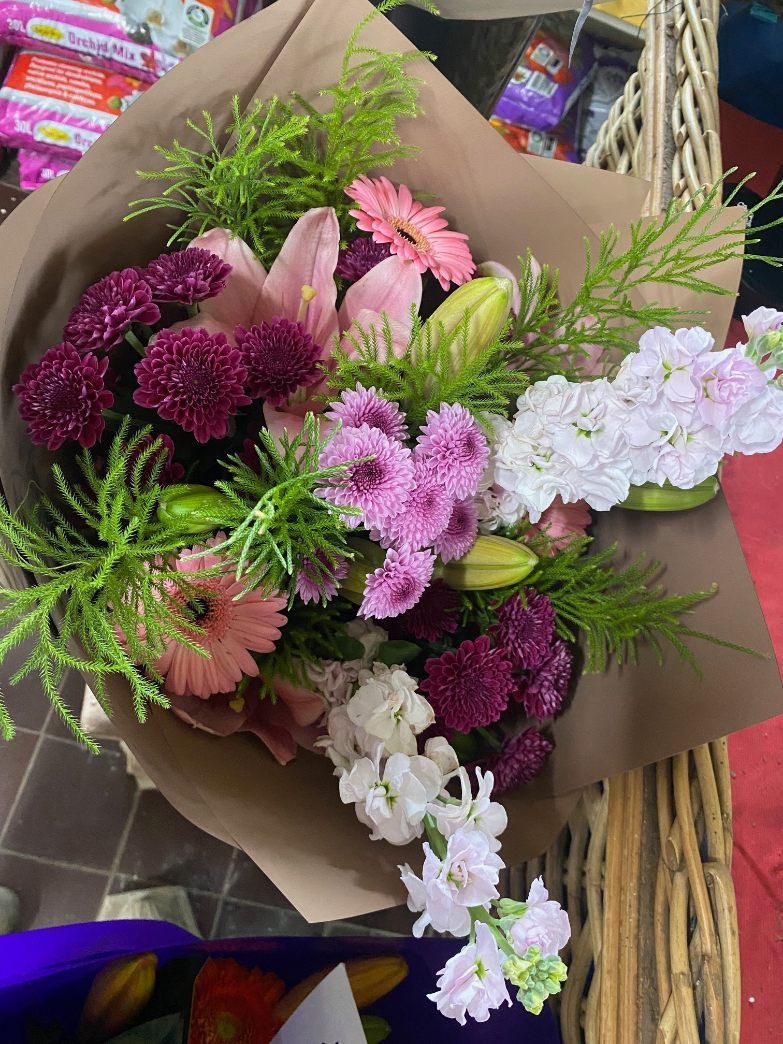A Bouquet of Flowers Wrapped in Brown Paper is Sitting on a Table — Wingham Nursery and Florist PTY Ltd In Wingham, NSW