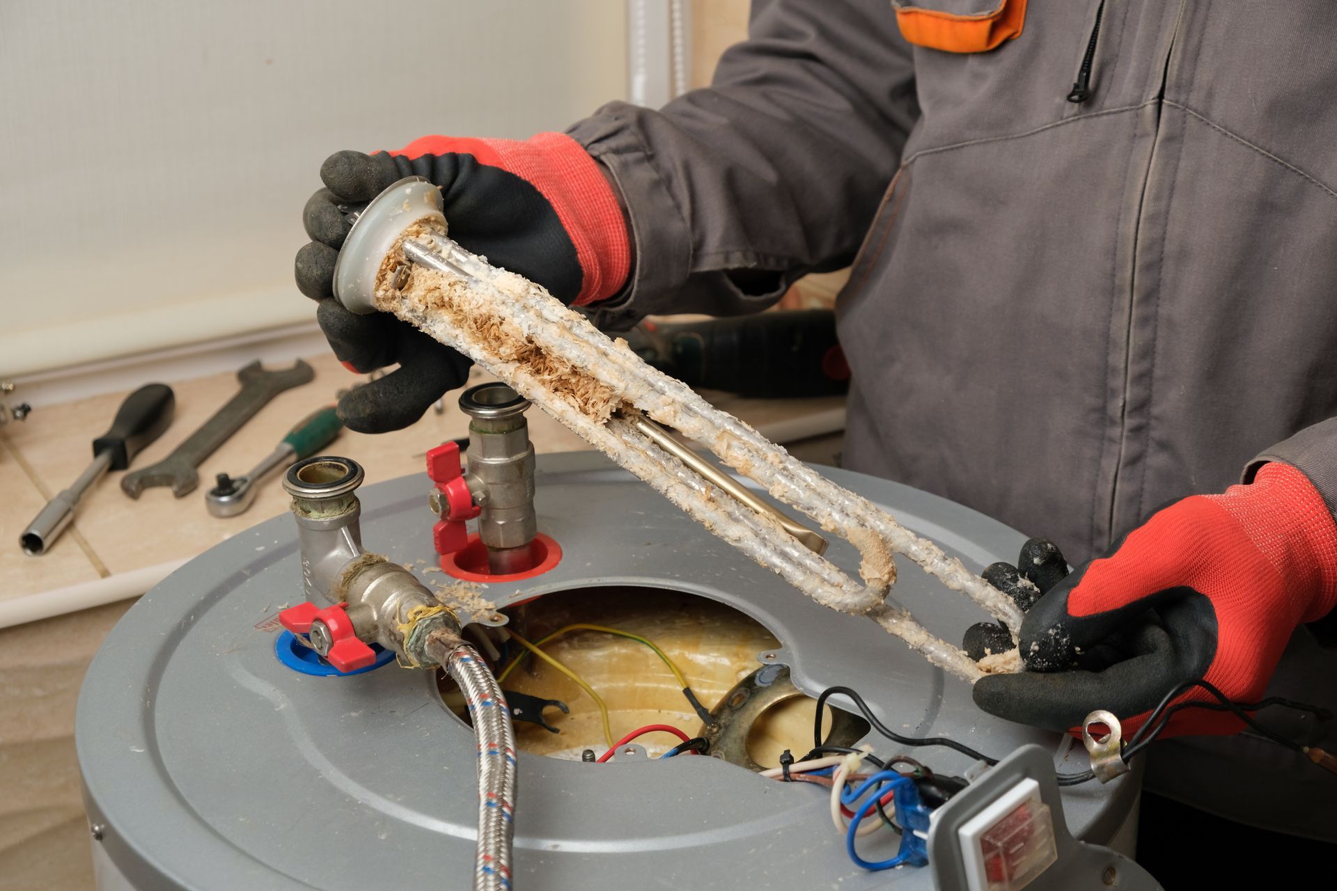 Technician holding a corroded pipe over an open utility meter box with tools nearby