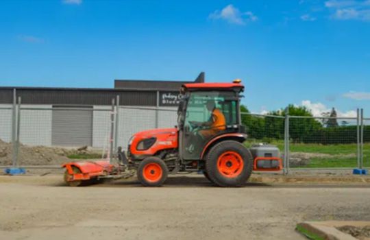 A man is driving a tractor on a dirt road.
