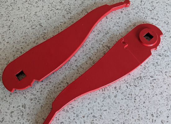 A pair of red spoons are sitting on a table.