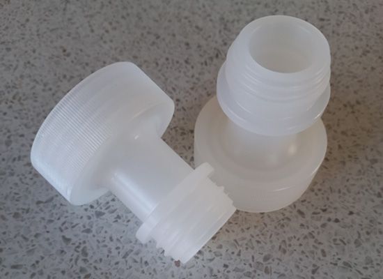 Two white plastic bottle caps are sitting on a table.