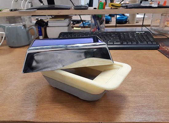 A container with the lid open is sitting on a wooden desk next to a keyboard.