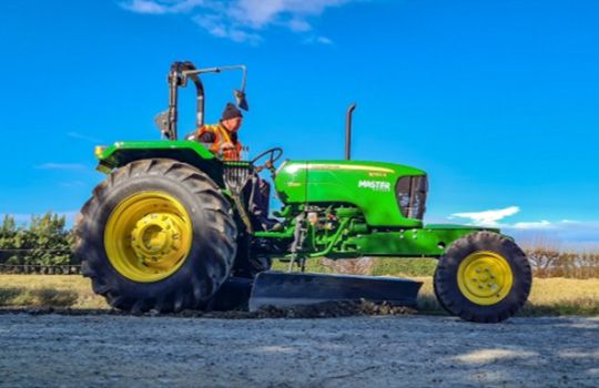 A green and yellow tractor is parked on the side of the road.