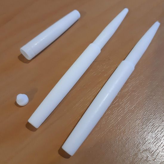 Three white pens are sitting on a wooden table
