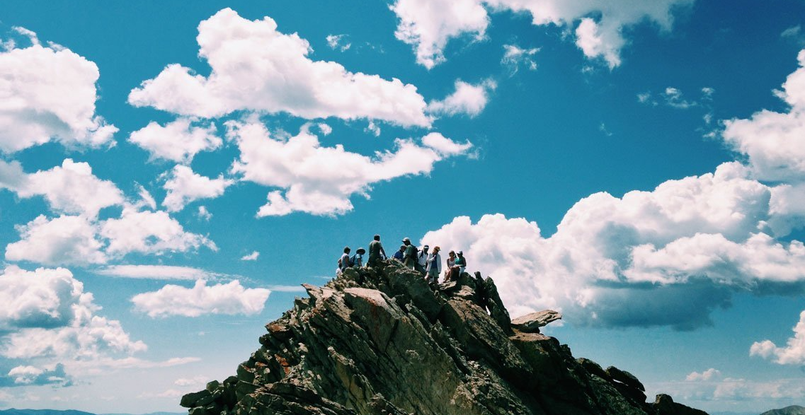 A group of people are standing on top of a mountain.