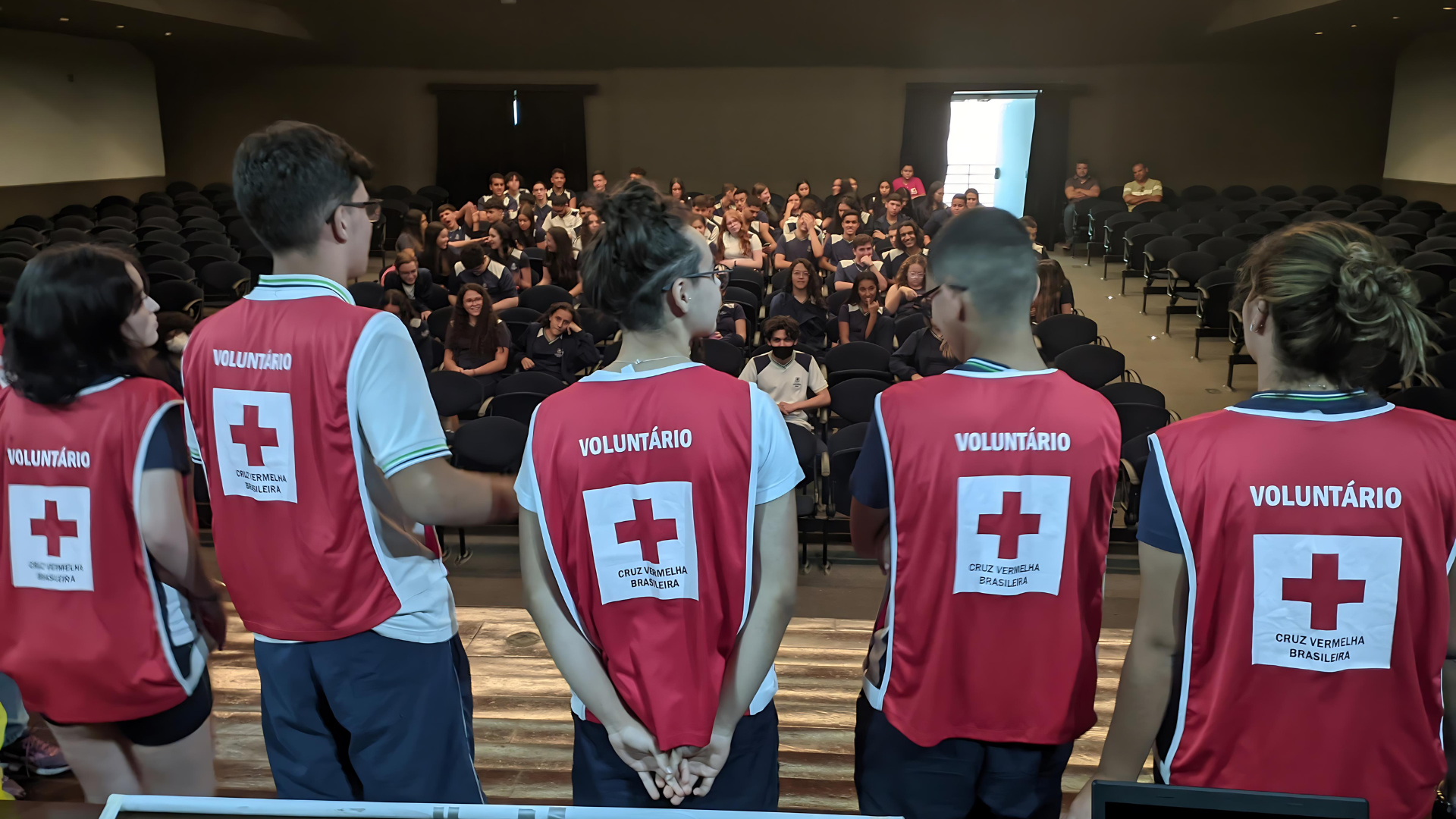 Um grupo de pessoas vestindo coletes vermelhos com uma cruz