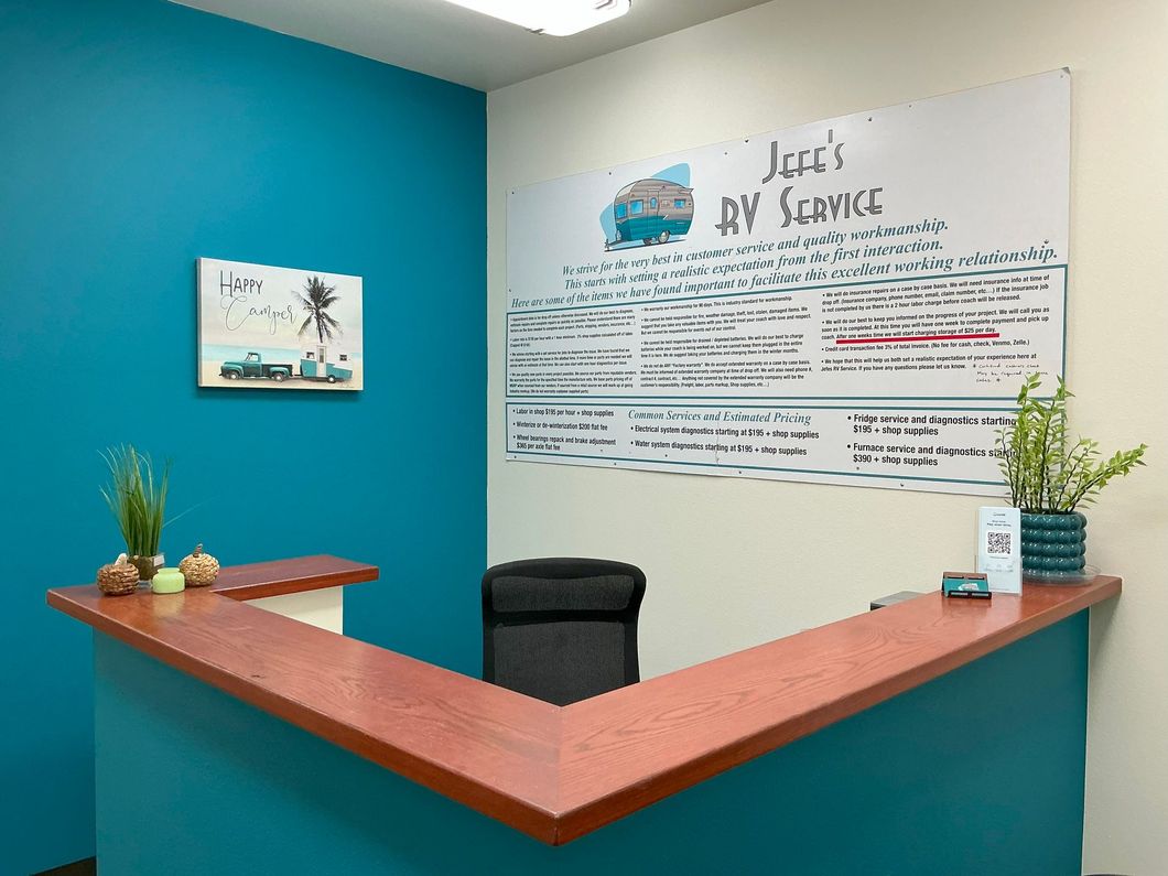 Reception desk with teal walls, a whiteboard, and a small palm tree artwork.
