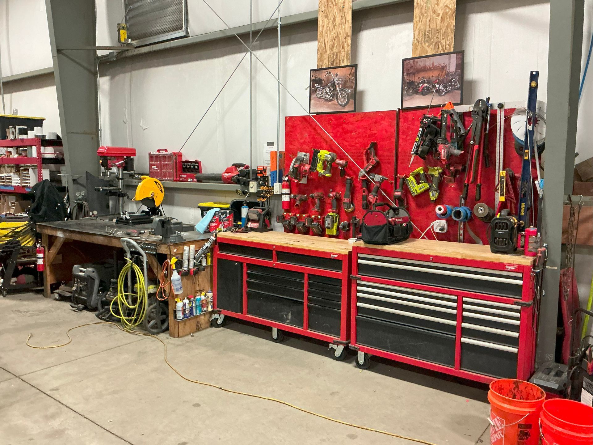 Workshop with tool benches, red toolboxes, pegboard with tools, and work surface.