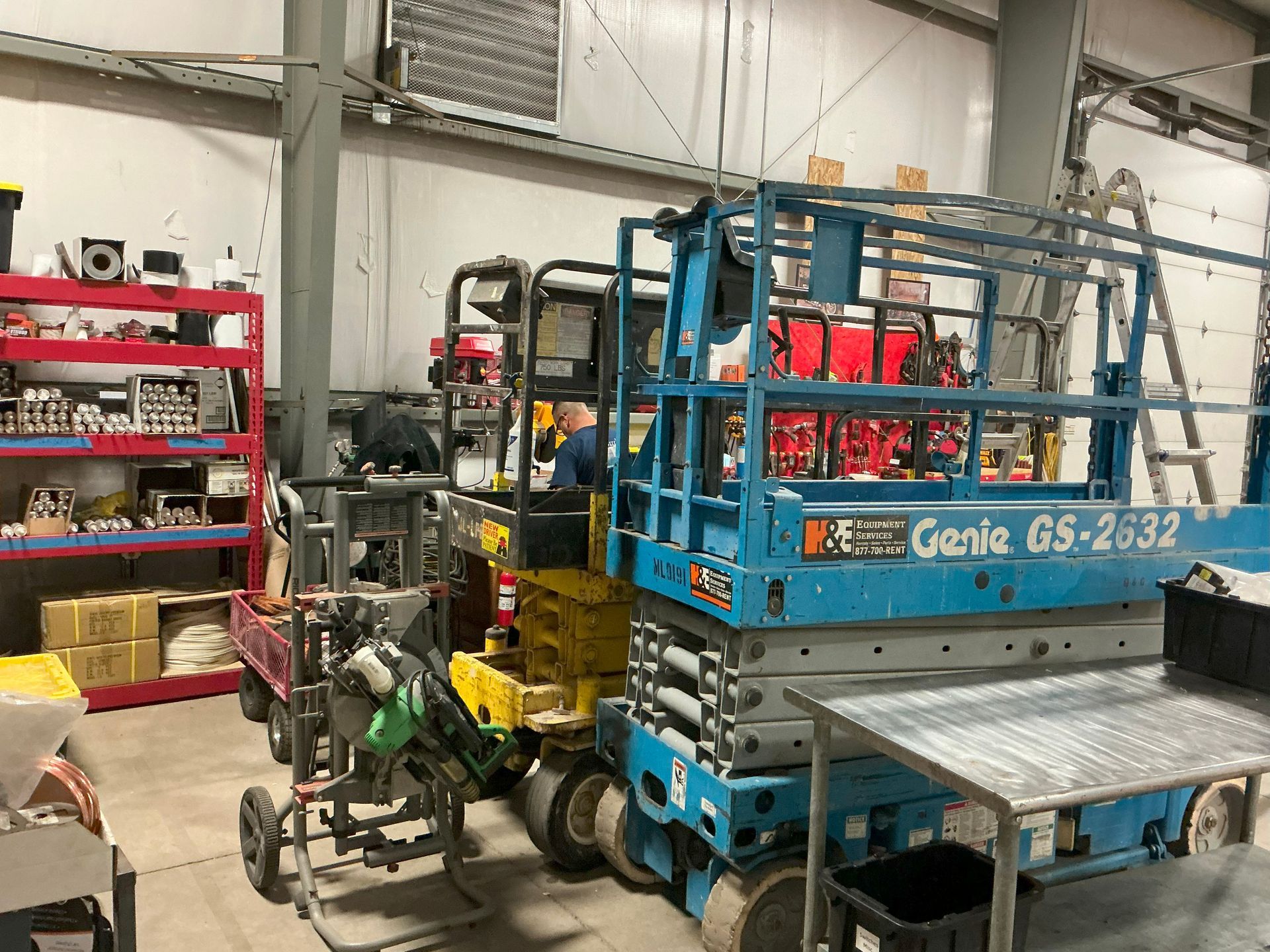 Workshop with a blue Genie GS-2632 lift, other equipment, and shelving.
