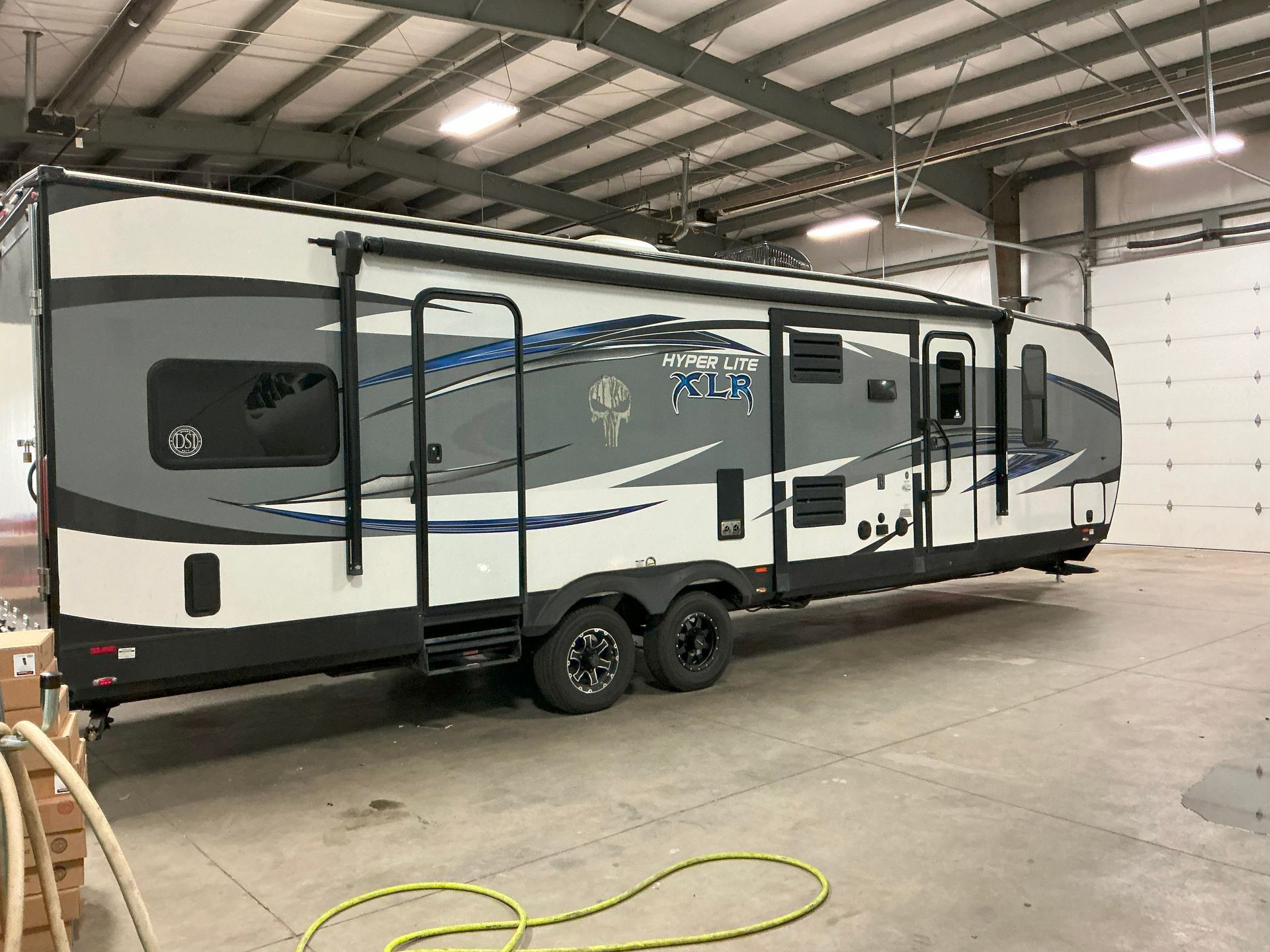 Large, gray and white recreational vehicle inside a garage.