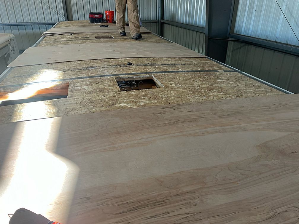 Person standing on a weathered wooden surface, with rectangular holes, in an industrial setting.