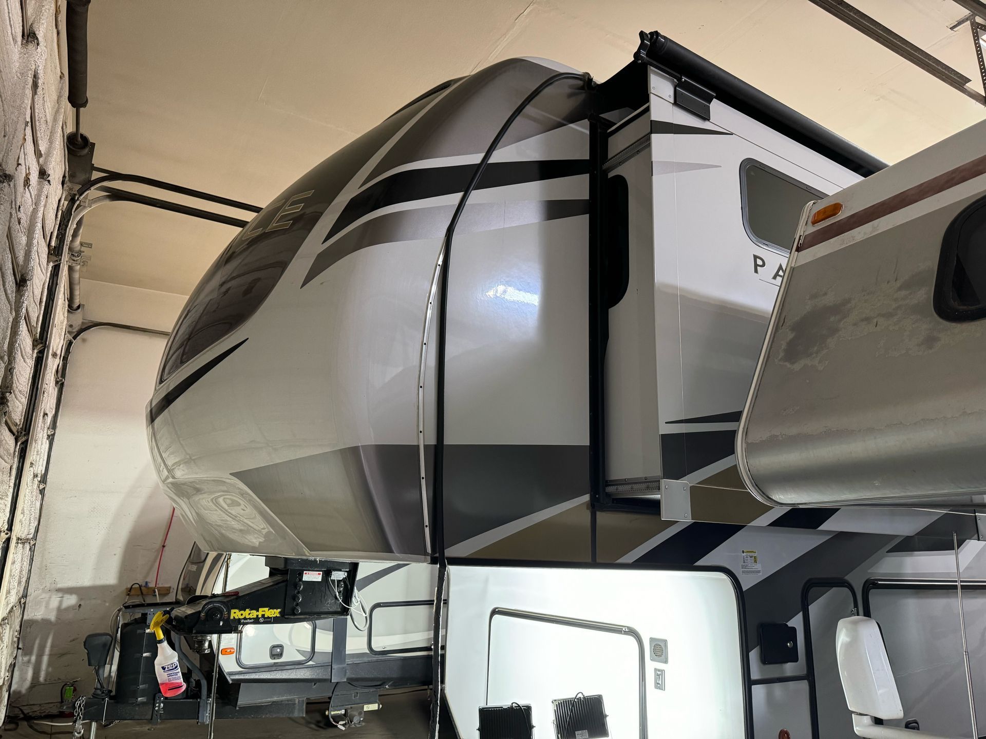 Fifth wheel RV, white and gray exterior, parked in a garage.