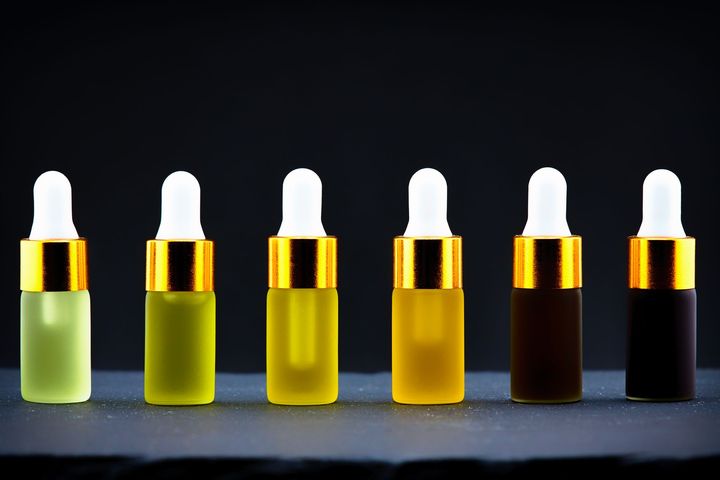 Six small dropper bottles with white caps in a row, showing a green-to-black color gradient.
