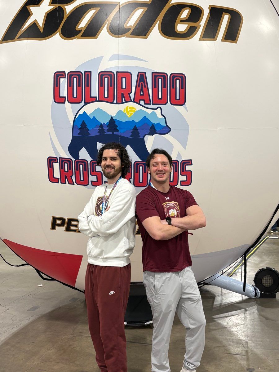 Two people posing in front of a Colorado Rockies-themed rocket at an indoor exhibit