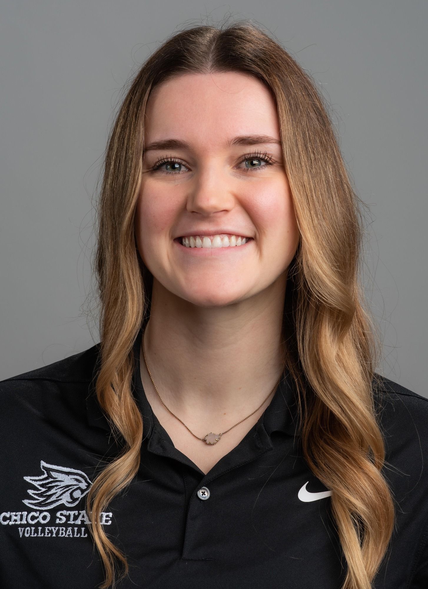 Smiling person in a black polo against a gray background