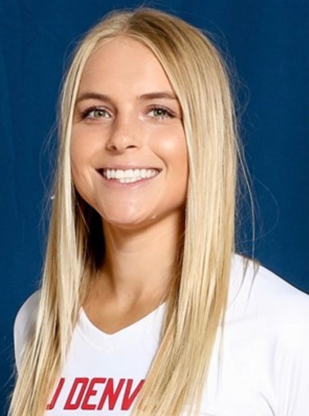 Blonde woman smiling, wearing a white shirt, with the word