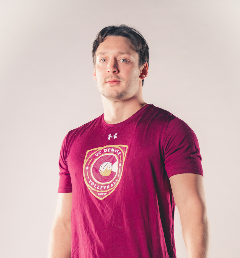 Man standing against a plain background wearing a maroon graphic T-shirt