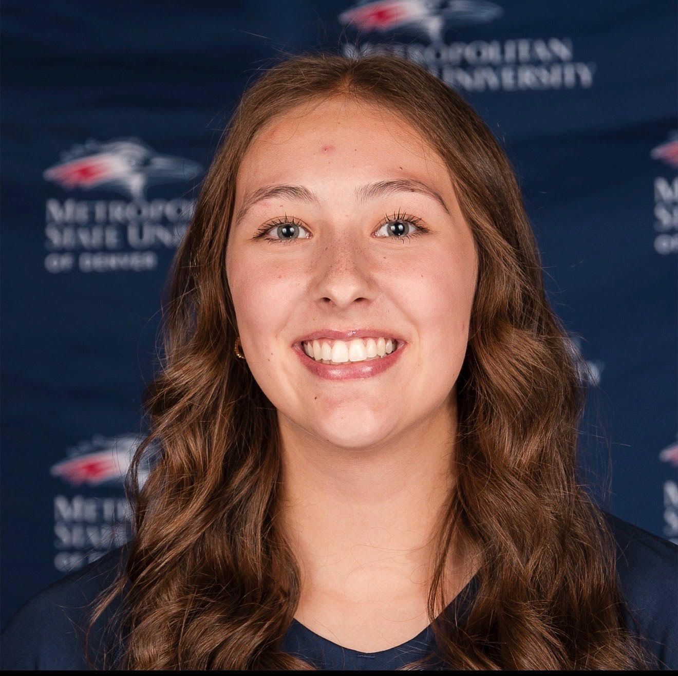 Smiling person in front of a blue Metro State University of Denver backdrop