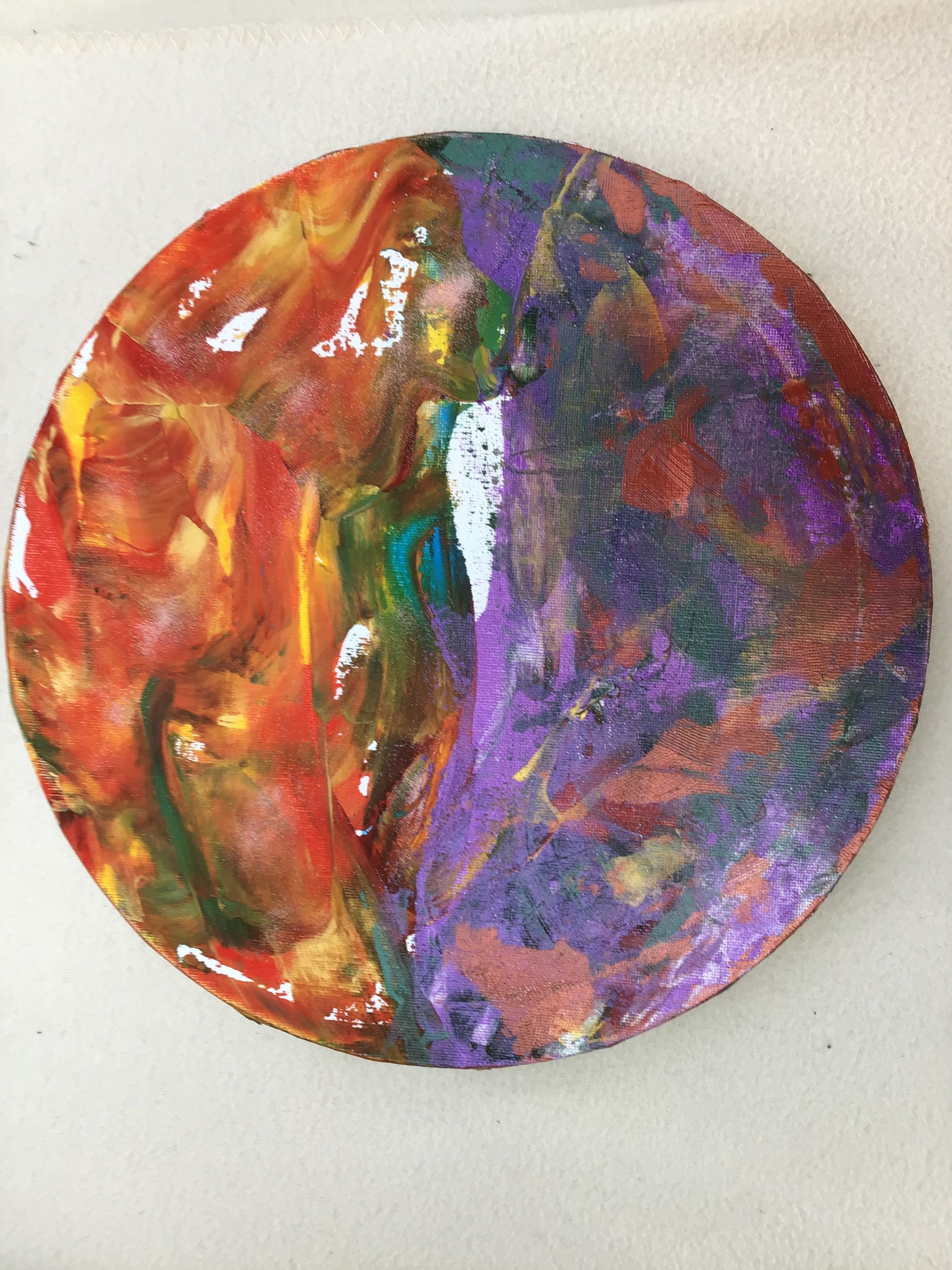 Abstract circular painting with swirling red, orange, green, and purple colors on white background