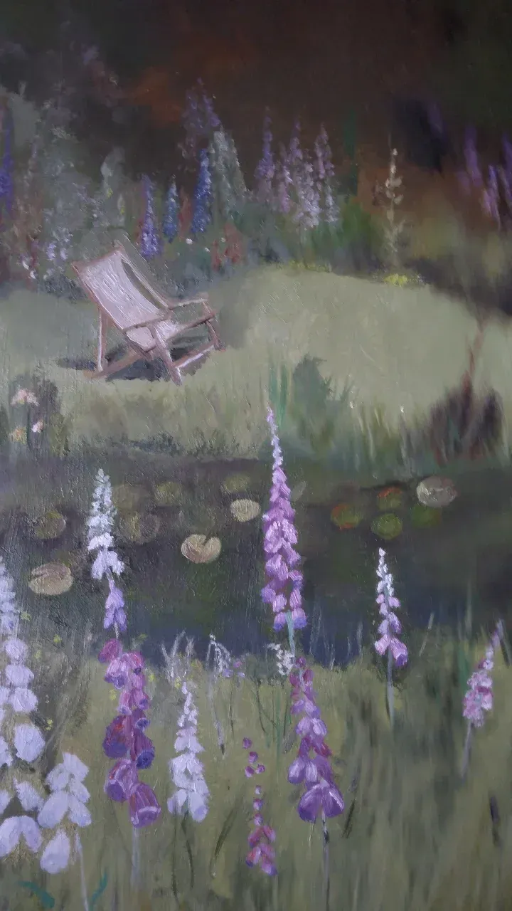 A garden chair on a grassy hill with purple wildflowers in the foreground